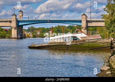 Halb versunkenes Vintage-Boot. Am Hackensack River in New Jersey, USA. Blick Richtung Norden auf die Zugbrücke auf der Winant Avenue, Route 46 East Stockfoto