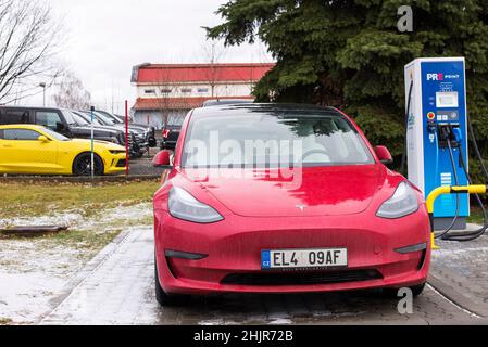 Roznov Tschechische Republik November 20th 2022 - Tesla Model S wird mit einem gelben Muschelwagen im Hintergrund aufgeladen Stockfoto