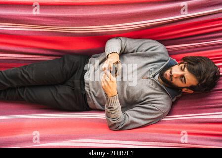 Hipster Mann mit Handy in einer Hängematte Stockfoto