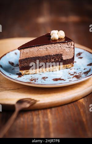 Schokoladen-Haselnusskuchen mit fünf Lagen Keks und Creme mit Schokoladenverglasung auf der Oberseite und ganzen Nüssen von Piemont. Serviert und dekoriert mit Kfs Stockfoto