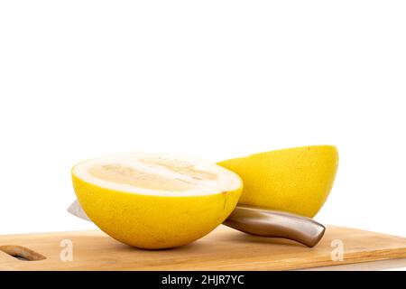 Zwei Hälften eines süßen Pomelos mit einem Messer auf einem hölzernen Schneidebrett, Makro, auf weiß isoliert. Stockfoto