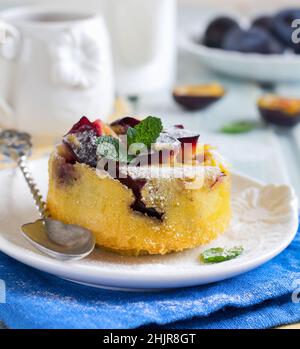 Hausgemachte Pflaumenklafoutis oder Pudding auf weißem Keramikplatte. Rustikale hausgemachte Pflaume Backwaren Selektive Konzentration. Stockfoto