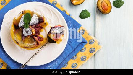 Hausgemachte Pflaumenklafoutis oder Pudding auf weißem Keramikplatte. Rustikale hausgemachte Pflaume Backwaren Selektive Konzentration. Stockfoto