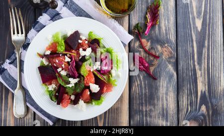Salat aus Rüben, Salat, Rote Beete, Grapefruit und Feta auf dem alten Holzhintergrund. Selektiver Fokus. Stockfoto