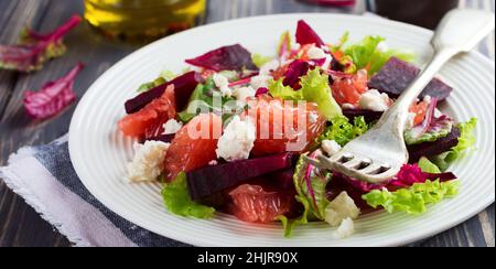 Salat aus Rüben, Salat, Rote Beete, Grapefruit und Feta auf dem alten Holzhintergrund. Selektiver Fokus. Stockfoto