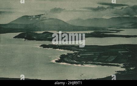 Der Hafen von Valentia und sein einsamer Leuchtturm kennen eine traurige, wilde Schönheit. Irland (1923) Stockfoto