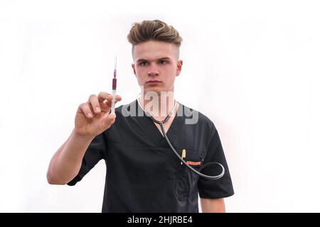 Arzt mit Spritze. Junger Arzt in Sanitäter Uniform hält Spritze in der Hand mit Handschuh isoliert auf weiß Stockfoto