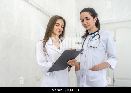 Lächelnde Ärzte jung und zuversichtlich posieren im Krankenhaus für Kamera Stockfoto