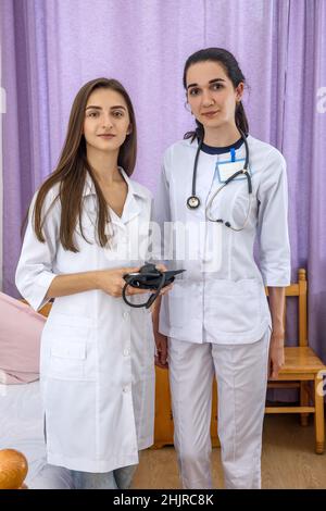 Lächelnde Ärzte jung und zuversichtlich posieren im Krankenhaus für Kamera Stockfoto