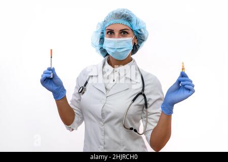 Ärztin in Schutzmaske und Handschuhen mit Spritze und Ampulle isoliert auf weiß Stockfoto