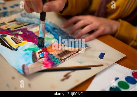 Nahaufnahme des lebendigen Aquarellmalprozesses. Pinsel in der Hand über Malerei. Bunte mittelalterliche Stadtstraße auf Papptafel. Stockfoto