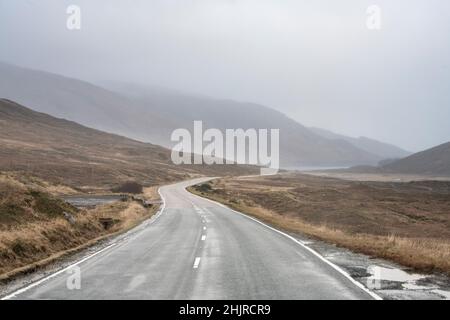 Blick in Strath Cluanie vom Pass aus, bevor die Straße an einem nassen und windigen Morgen auf der Road to the Isles in Glen Shiel abfällt. Stockfoto