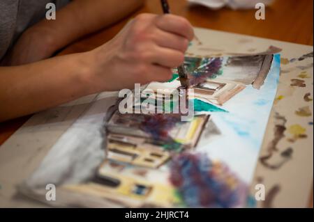 Nahaufnahme des lebendigen Aquarellmalprozesses. Pinsel in der Hand über Malerei. Bunte mittelalterliche Stadtstraße auf Papptafel. Stockfoto