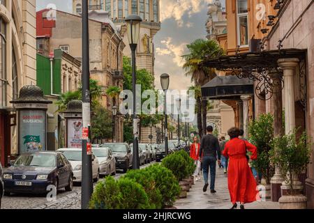 Frau in rotem Kleid, die mit Menschen die Straße, Batumi Straße, geht Stockfoto