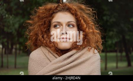 Zufrieden Rothaarige Frau mit blauen Augen in Decke draußen bedeckt Stockfoto