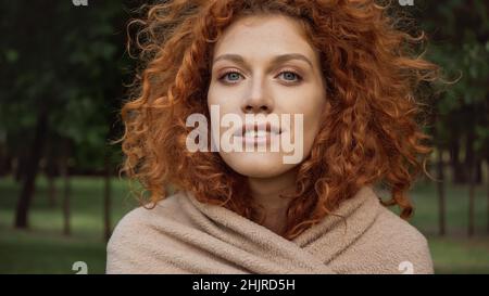 Hübsche Rothaarige Frau mit blauen Augen, die draußen mit einer Decke bedeckt sind Stockfoto