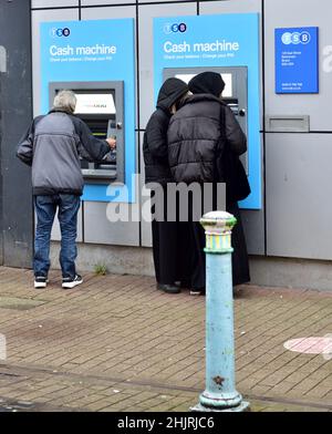 Personen, die einen Geldautomaten in der Wand der TSB Bank benutzen Stockfoto