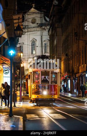 Lissabon, Portugal - 18 2021. November: Eine ikonische Straßenbahn wartet nachts an einer Ampel im historischen Zentrum von Lissabon. Stockfoto