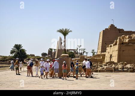 Touristen auf Exkursionen in Karnak Tempel. Reisegruppe in der Nähe der Skarabäus-Statue. Berühmtes ägyptisches Wahrzeichen mit Hieroglyphen, verfallenen Tempeln und Stockfoto