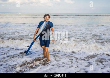 Mann, Surfbrett über seinen Kopf. Nahaufnahme von hübscher Kerl mit Surfbrett auf dem Kopf am Strand. Portrait von Mann Surfboard auf hid Kopf und Stockfoto