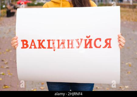 Eine Frau hält ein Plakat mit Text, übersetzt aus dem Ukrainischen: Get impfed Stockfoto