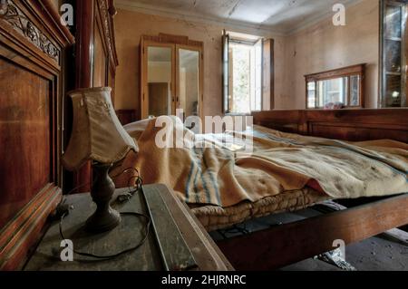 Italien, Den 20. Januar 2021. Schlafzimmer mit Doppelbett und Kleiderschrank in einem verlassenen Haus. Urbex Stockfoto