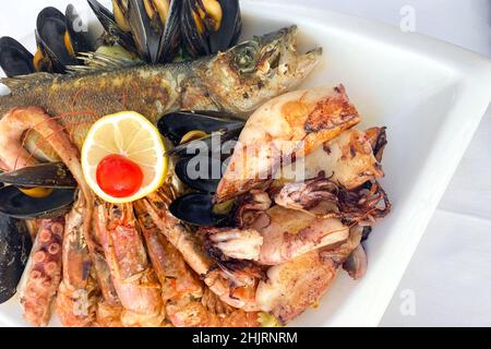 Frisch gefangene und zubereitete Meeresfrüchte: Gegrillte Garnelen, Tintenfische, Tintenfische, Muscheln und Meeresfische auf weißem Tischhintergrund. Mittagessen im Seafood Restaurant auf Stockfoto