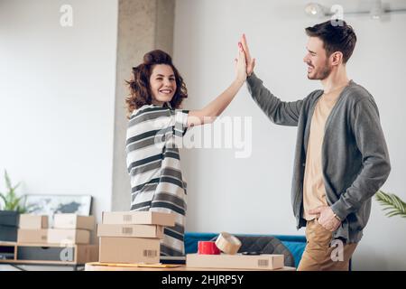 Fröhliche Mitarbeiter im Online-Shop begrüßen sich gegenseitig Stockfoto