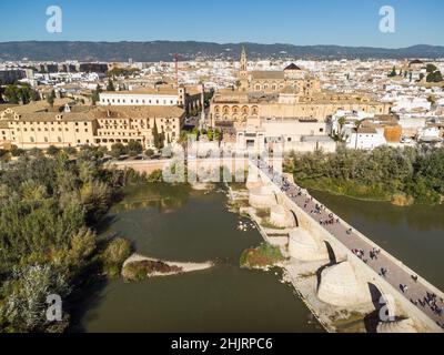 Dramatische Luftaufnahme der berühmten römischen Brücke über dem Guadalquivir-Fluss entlang der Altstadt von Cordoba in Andalusien in Südspanien an einem sonnigen Tag Stockfoto