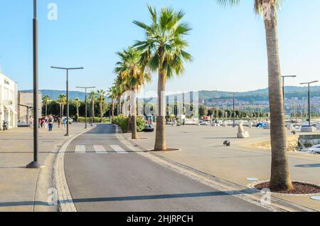 Küstenstraße mit Palmen an einem schönen sonnigen Tag in Koper, Slowenien. Menschen, die entlang der Marina spazieren. Stockfoto