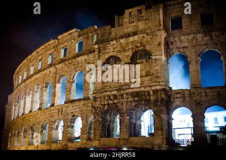 Die Arena von Pula, das antike römische Amphitheater in Kroatien bei Nacht. Es ist Gastgeber eines Live Concert. Rauch kommt aus den gewölbten Wänden. Stockfoto