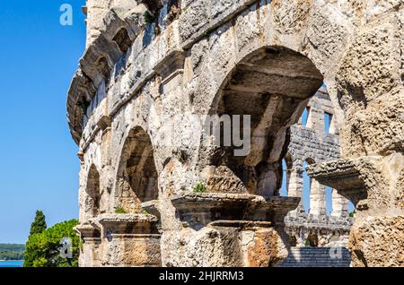 Die Fassade Der Pula Arena. Altes römisches Amphitheater mit restaurierten Bogenmauern in Kroatien. Gut Erhaltenes Denkmal. Heller Blauer Himmel Hintergrund Stockfoto