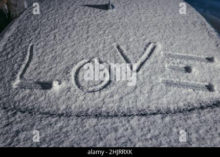 Wort Liebe geschrieben auf einem Auto mit Schnee bedeckt Stockfoto