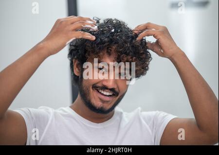 Mann, der das Haarstyling-Produkt auf seine Locken anwendet Stockfoto