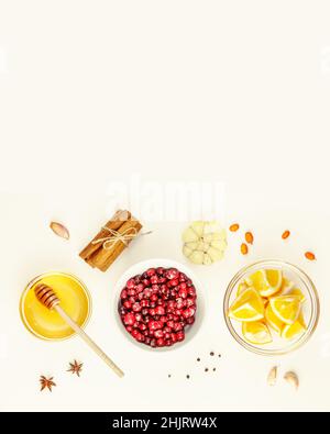 Gesunde Lebensmittelzusammensetzung mit wilden Preiselbeeren, Honig, Knoblauch, Sanddorn, Zimtstangen und Gewürzen auf weißem Hintergrund mit Kopierfläche. Virus de Stockfoto