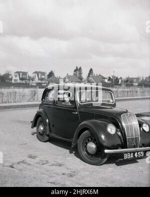 1950, historisches, reifes Paar im Auto der Ära, möglicherweise ein britischer Ford, geparkt an der Küste, England, Großbritannien. In dieser Zeit mit wenig Verkehr und ohne Parkbeschränkungen war es eine beliebte Zeit, mit dem Auto zu fahren. Stockfoto