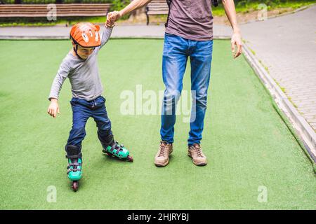 Vati lehrt Sohn im Park zu rollerblade Stockfoto