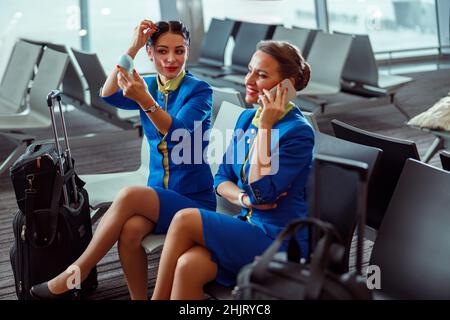 Fröhliche Frauen Stewardessen warten auf den Flug am Flughafen Stockfoto