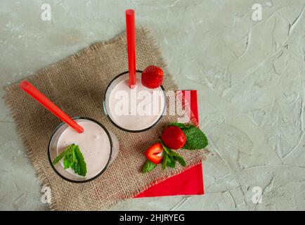 Köstlicher Milchshake mit Erdbeeren in hohen Gläsern, Erdbeeren und Minze Stockfoto