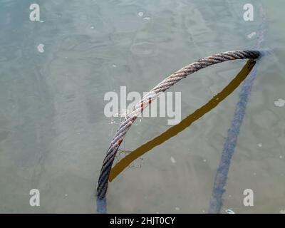 Im Sommer liegt im Fluss ein eisernes Kabel Stockfoto