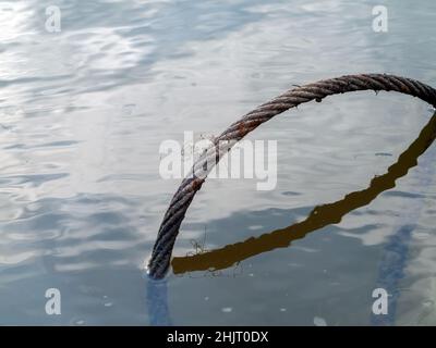 Im Sommer liegt im Fluss ein eisernes Kabel Stockfoto