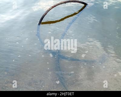 Im Sommer liegt im Fluss ein eisernes Kabel Stockfoto