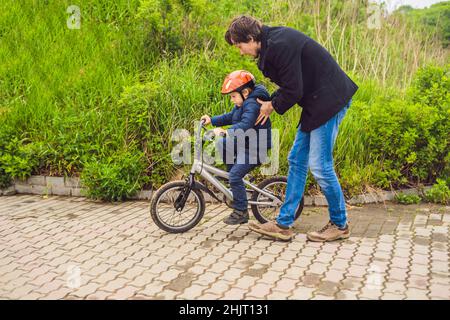 Vati lehrt Sohn ein Fahrrad im Park zu fahren Stockfoto