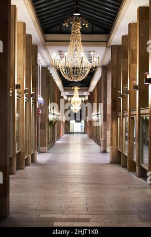 Ein beleuchteter Kronleuchter in einer Allee aus Steinsäulen. Urbane Architektur in der Nacht. Stockfoto