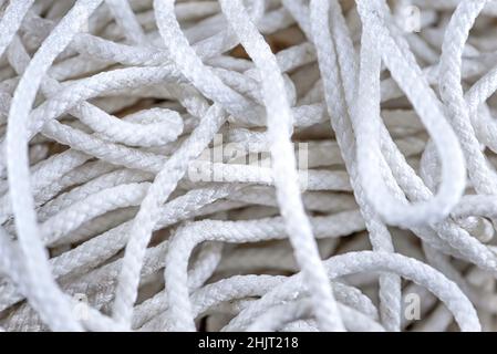 Dickes, verworrenes weißes Seil aus der Nähe. Nahaufnahme eines abgenutzten Bootsseils als nautischer Hintergrund.