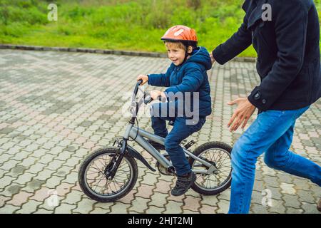 Vati lehrt Sohn ein Fahrrad im Park zu fahren Stockfoto