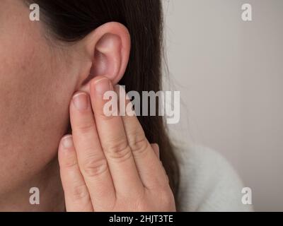 Frauen mittleren Alters, die an Ohrschmerzen und Tinnitus leiden. Die Ursache für Ohrschmerzen sind Ohr, Wachsküche, ein Fremdkörper im Ohr, Sinusinfektion oder Stockfoto
