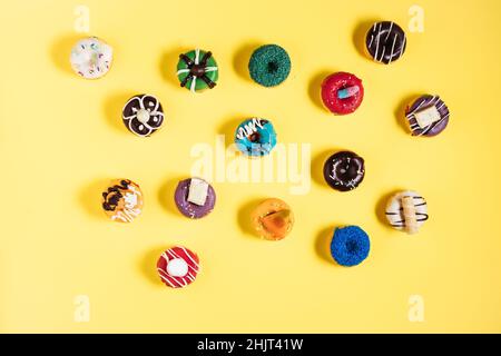 Bunte Donuts oder Donuts in verschiedenen Formen auf gelbem hellem Hintergrund. Farbenfrohes und glückliches Bild und Konzept. Stockfoto