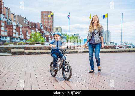 Mama lehrt Sohn ein Fahrrad im Park zu fahren Stockfoto