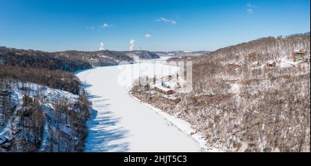 Luftdrohnenaufnahme des schneebedeckten und gefrorenen Cheat River, der durch die Berge in Richtung des Sees in der Nähe von Morgantown in West Virginia fließt Stockfoto